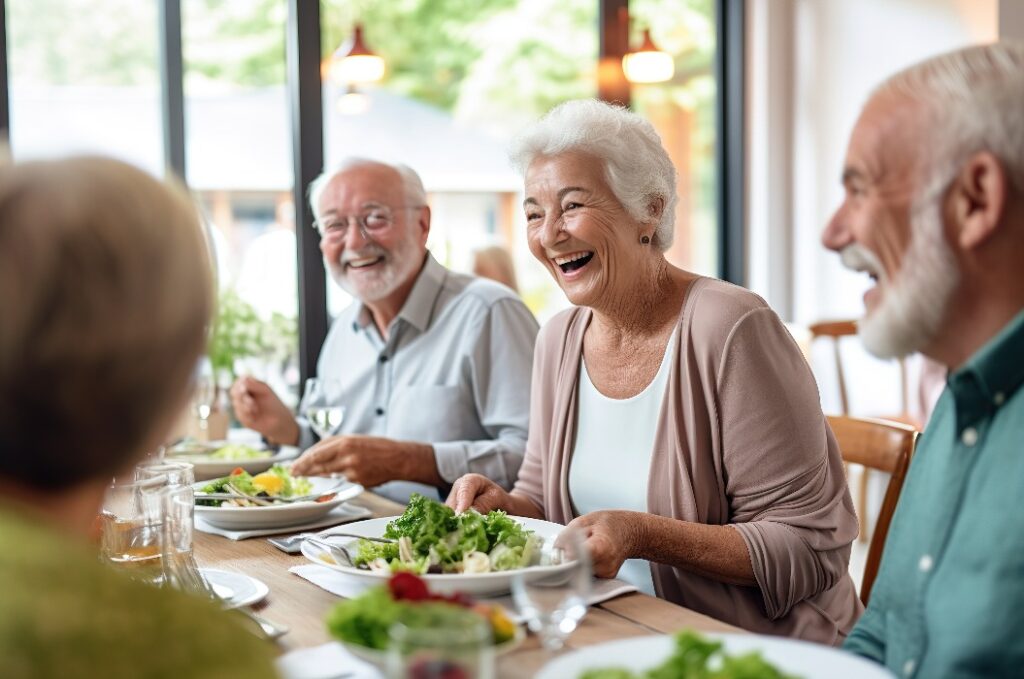 Senioren beim Essen in einer geselligen Runde am Essenstisch. Kantine im Altersheim und gesunder Nahrung. Gemeinsam speisen im Alter als Rentner.